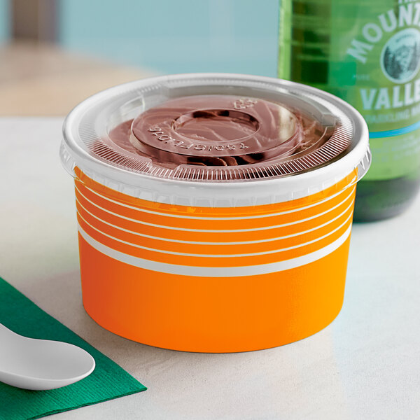 A close-up of a Choice orange paper frozen yogurt container with a plastic lid.