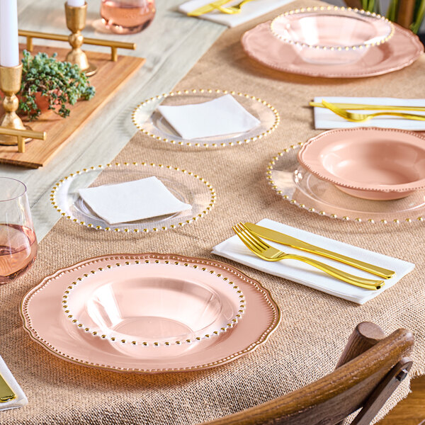 A table set with Visions clear plastic plates with gold beaded rims and gold accents.