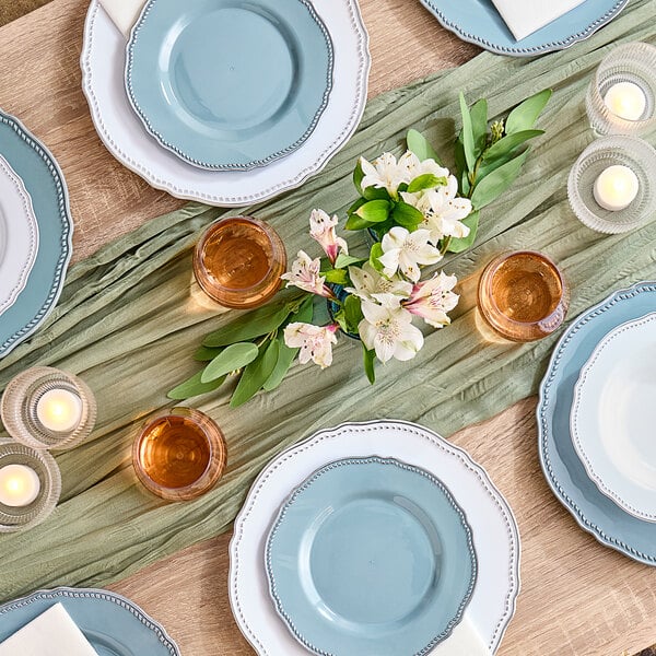 A table set with Visions blue plastic plates with silver vintage rims and candles.