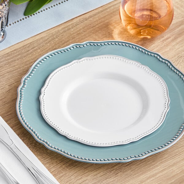 A white Visions plastic plate with a silver vintage rim on a table with a silver fork.