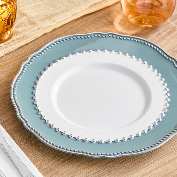 A Visions white plastic plate with a silver beaded rim on a table.