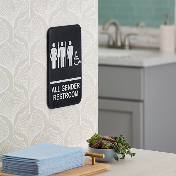 A Lavex black and white plastic restroom sign with the words "All Gender" and braille.
