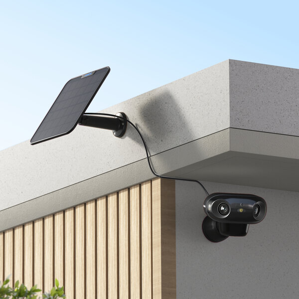 A Reolink solar-powered camera attached to a wall with a solar panel.