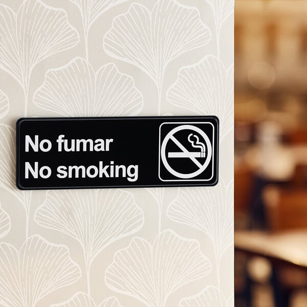 A Lavex black and white sign on a wall that says "No Fumar / No Smoking"