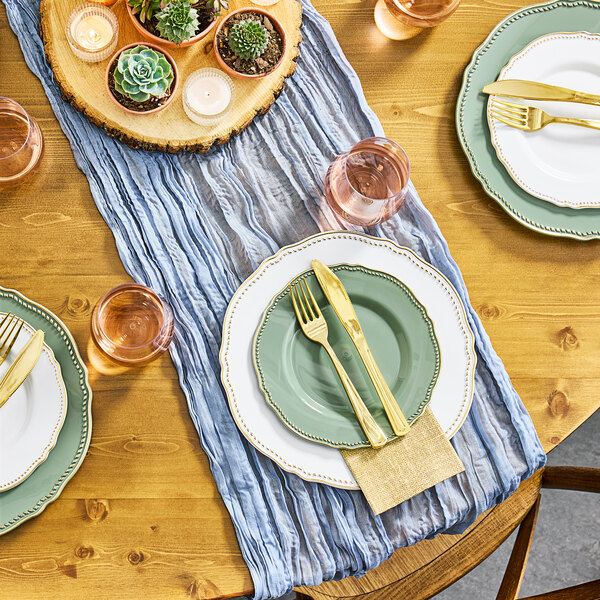 Visions Eucalyptus plastic plates with gold vintage rims on a table with plates and utensils.