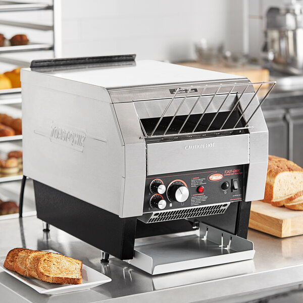 A Hatco Toast Qwik conveyor toaster on a counter with bread.