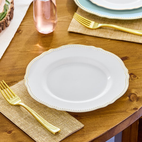 A table setting with a Visions white plastic plate and gold fork.