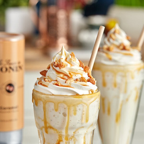 Two milkshakes with Monin Caramel Flavoring Sauce and whipped cream on top.