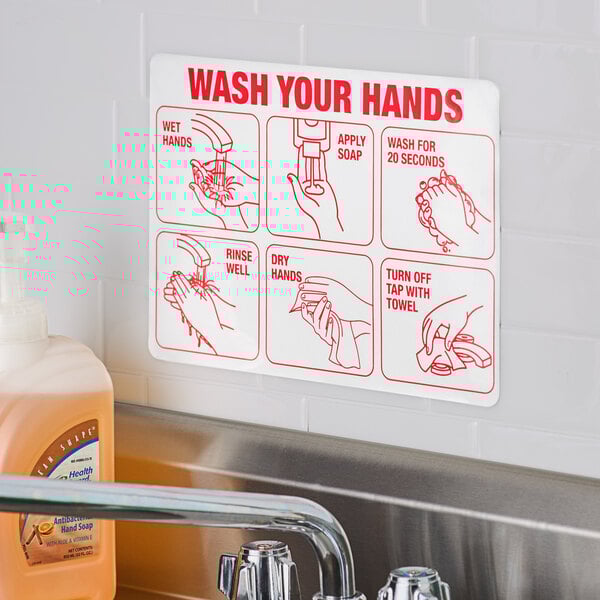 A white rectangular sign with red text that says "Wash Your Hands" above a sink.