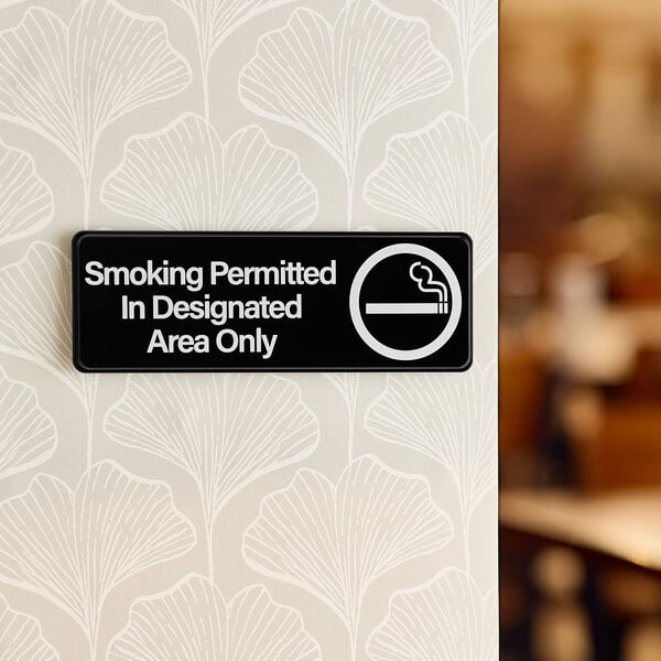 A Lavex black sign with white text that says "Smoking Permitted In Designated Areas Only"