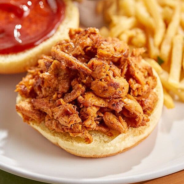 A close up of a sandwich with Barvecue pulled pork and fries.
