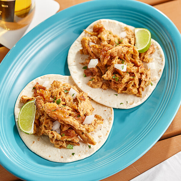 A plate with a taco filled with Barvecue Plant-Based Vegan Wood-Smoked Carnitas and lime slices.