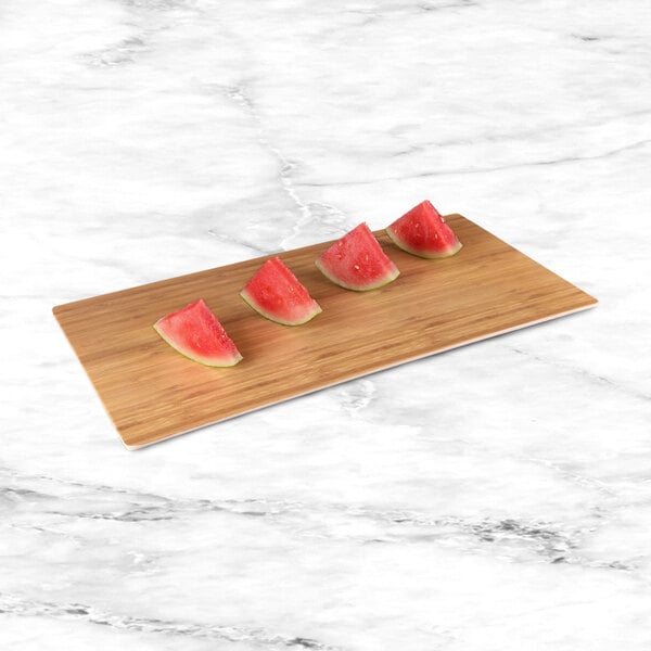 Watermelon slices on a rectangular faux bamboo melamine serving board.