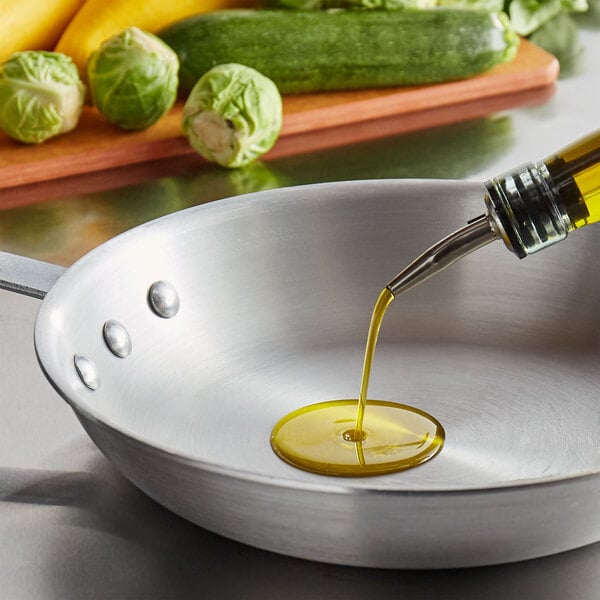 A close up of a frying pan with Extra Virgin Olive Oil being poured into it.