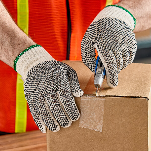 A person in Lavex work gloves using a cutter to cut a cardboard box.