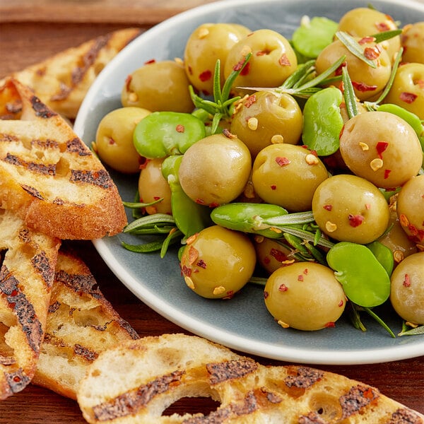 A plate of Spanish Queen Olives with bread on a table in a salad bar.