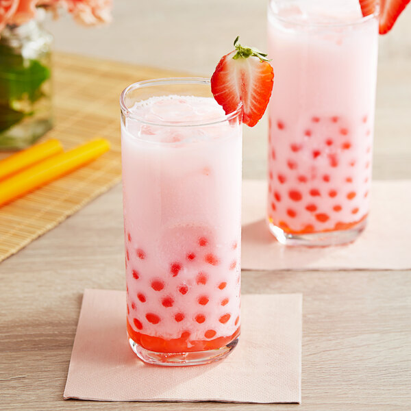 Two glasses of pink drinks topped with strawberries.