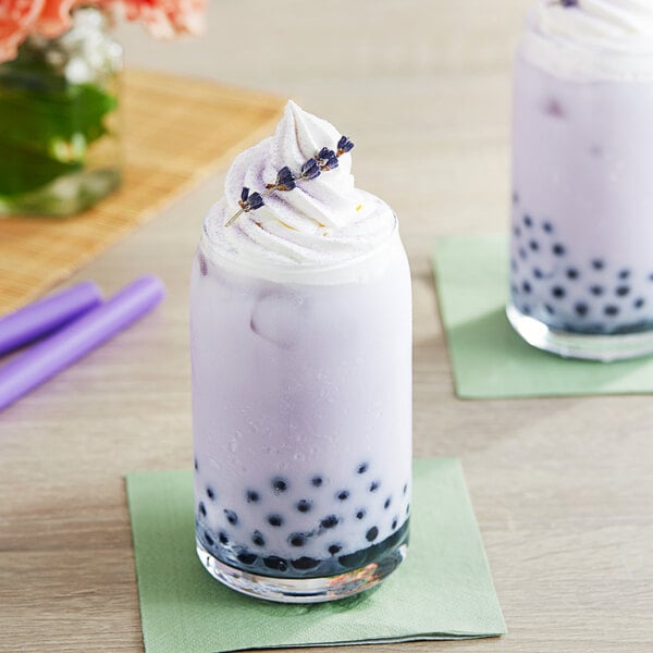 A glass of purple bubble tea with a lavender topping and a straw.