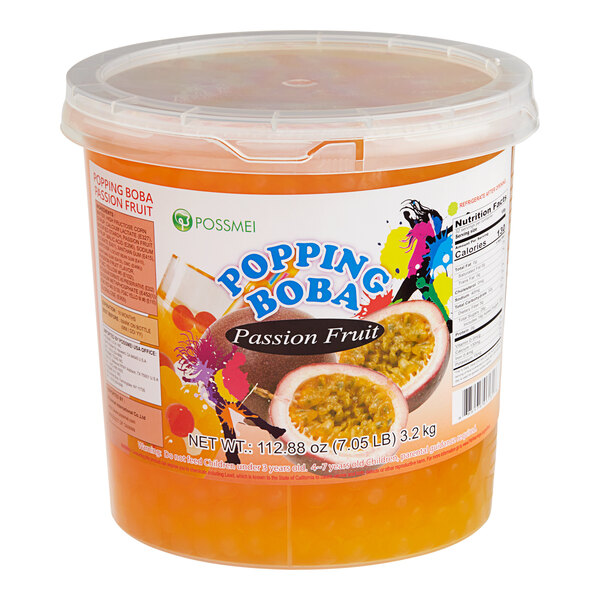 A plastic container of Possmei Passion Fruit Popping Boba on a table in a juice bar.