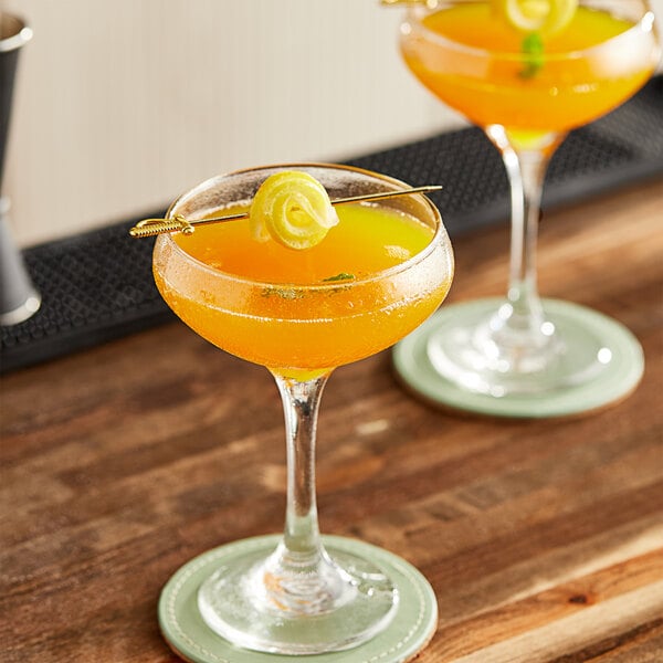 A pair of glasses with passion fruit drinks in them on a counter.