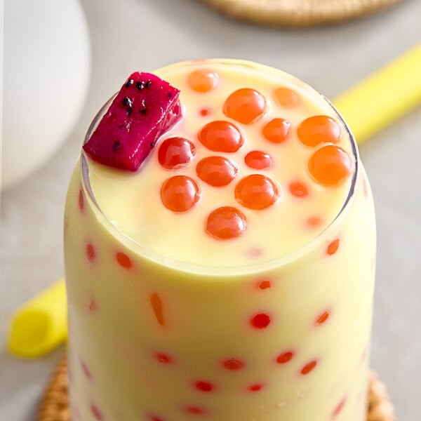 A glass of milk with red and white Possmei Dragon Fruit Popping Boba.