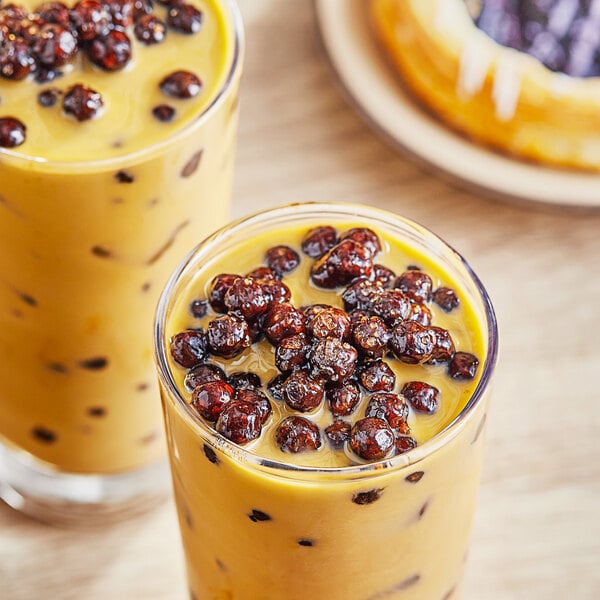 A glass of milk with brown Possmei Tapioca Boba Pearls on top.