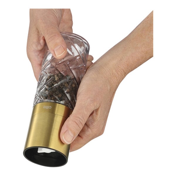 A person's hand using a Cilio gold salt/pepper mill.