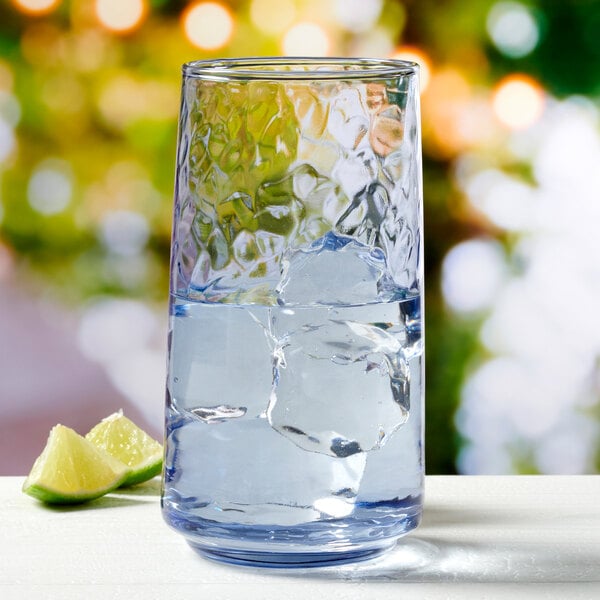A close-up of an Anchor Hocking Coastal Blue cooler glass filled with water, ice, and a lime slice.