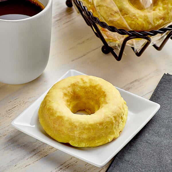 A round yellow Southern Roots lemon drop cake donut on a white plate.