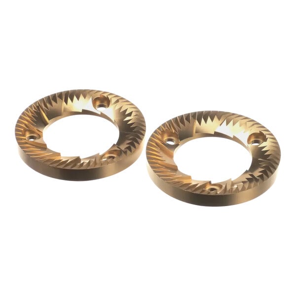 A pair of gold titanium-coated metal grinding discs with holes in the center.