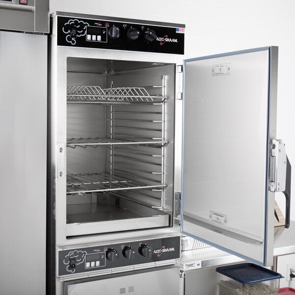 An open Alto-Shaam commercial smoker oven with food on racks inside.