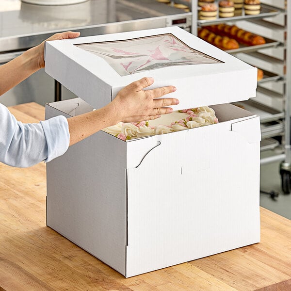 A woman opening a Southern Champion cake box with a window.