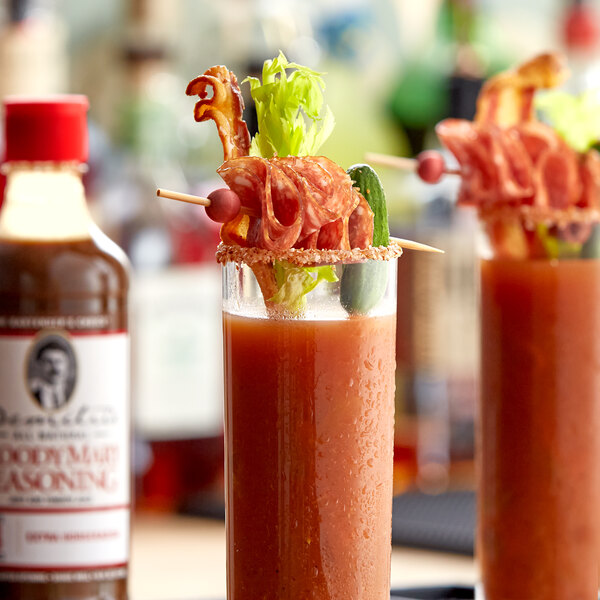 A glass of red liquid with a Demitri's Extra Horseradish Bloody Mary Concentrated Seasoning label on the table.