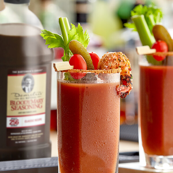 A glass of Demitri's Classic Bloody Mary drink with a straw and garnish on a table.