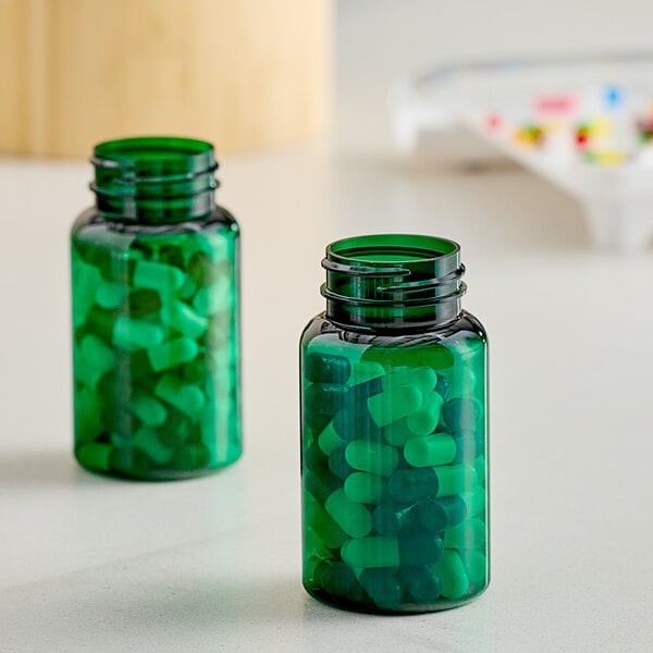 Two green PET packer bottles with green pills inside.