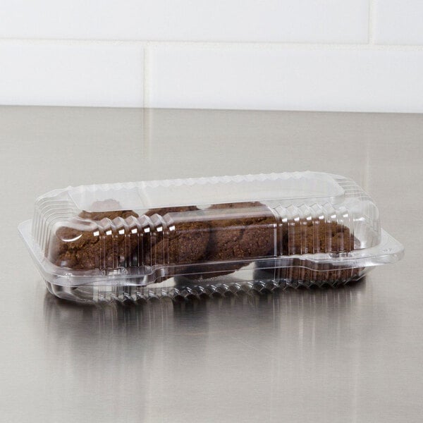 A Dart clear plastic container with brown cookies inside on a counter.