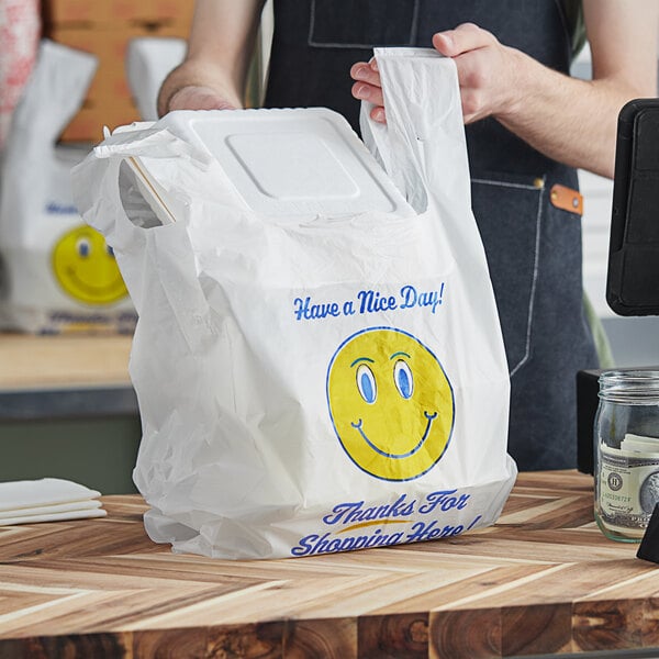 A man holding a white plastic Source Direct Inc. T-shirt bag with a smiley face on it.