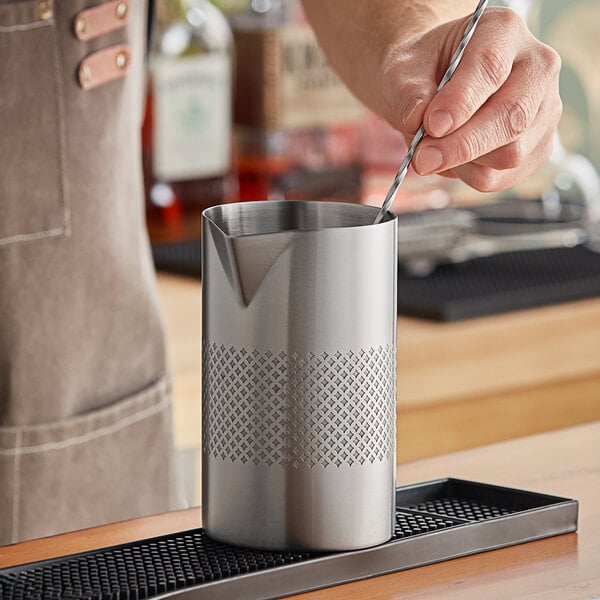 A person stirring a drink in a silver Barfly stainless steel mixing tin.