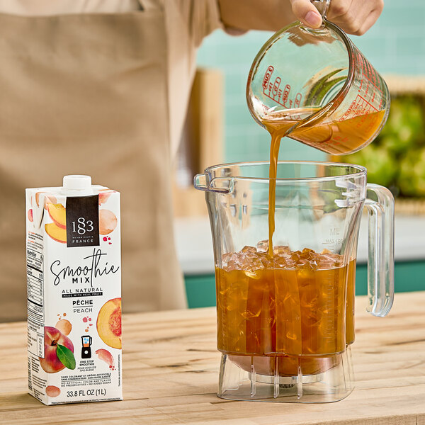 A person pouring 1883 Maison Routin Peach Smoothie Mix into a blender.