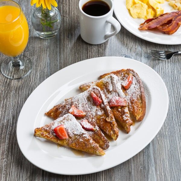 A Libbey white porcelain platter with French toast and strawberries on a table.