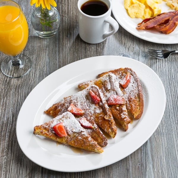 A large white oval porcelain platter with a wide rim, shown holding slices of French toast with strawberries and powdered sugar.