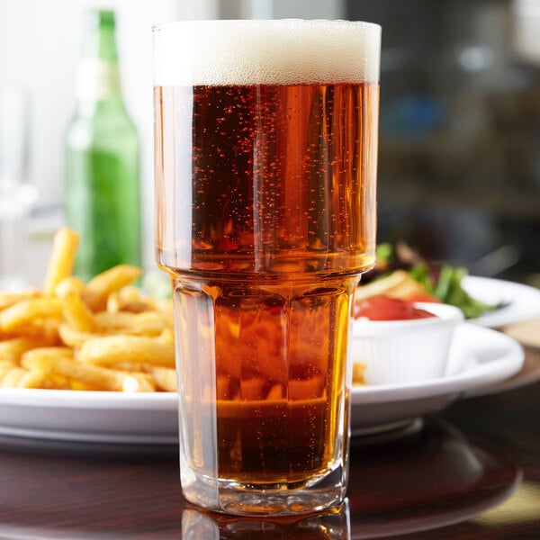 A Libbey Gibraltar stackable cooler glass of beer on a table with fries.