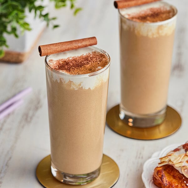 Two glasses of Cappuccine Supreme Spiced Chai Frappe with cinnamon sticks on top.