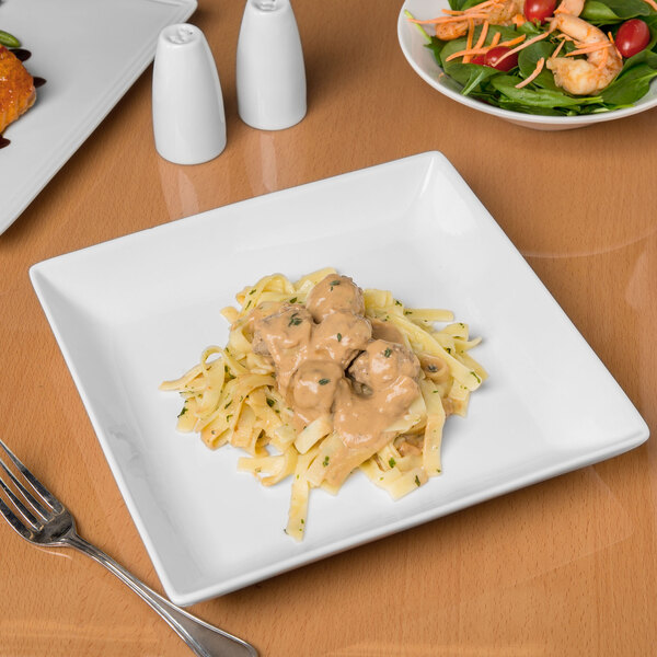 A white square porcelain coupe plate with a serving of pasta and creamy sauce.