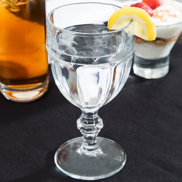 A Libbey Gibraltar goblet filled with water and ice with a lemon wedge on the rim.