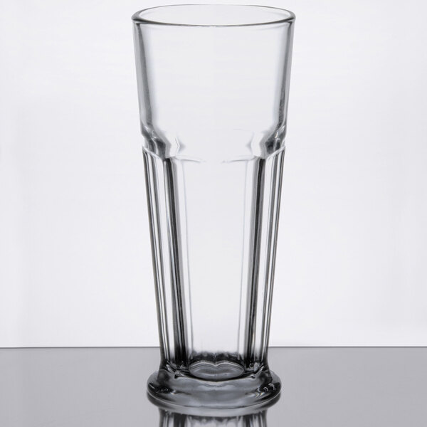 A close-up of a Libbey Gibraltar footed Pilsner glass on a table with a heart on the bottom.