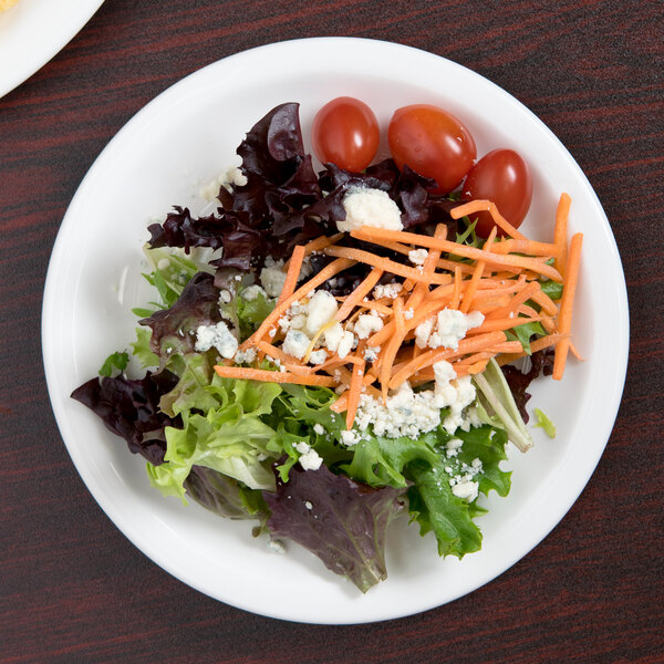 A Libbey white porcelain plate with a salad, tomatoes, and cheese.