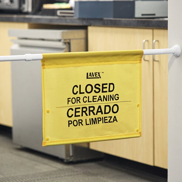 A yellow Lavex hanging doorway safety sign that says "Closed for Cleaning"