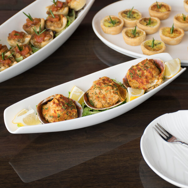 A Libbey white porcelain canoe plate with food on it on a table.