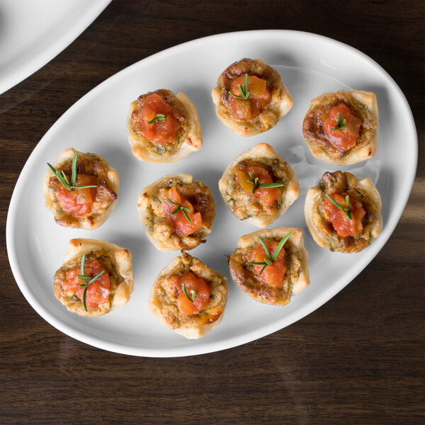 A Libbey white porcelain tray with small appetizers on a table.